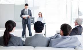 Présentateur debout face à un petit groupe assis